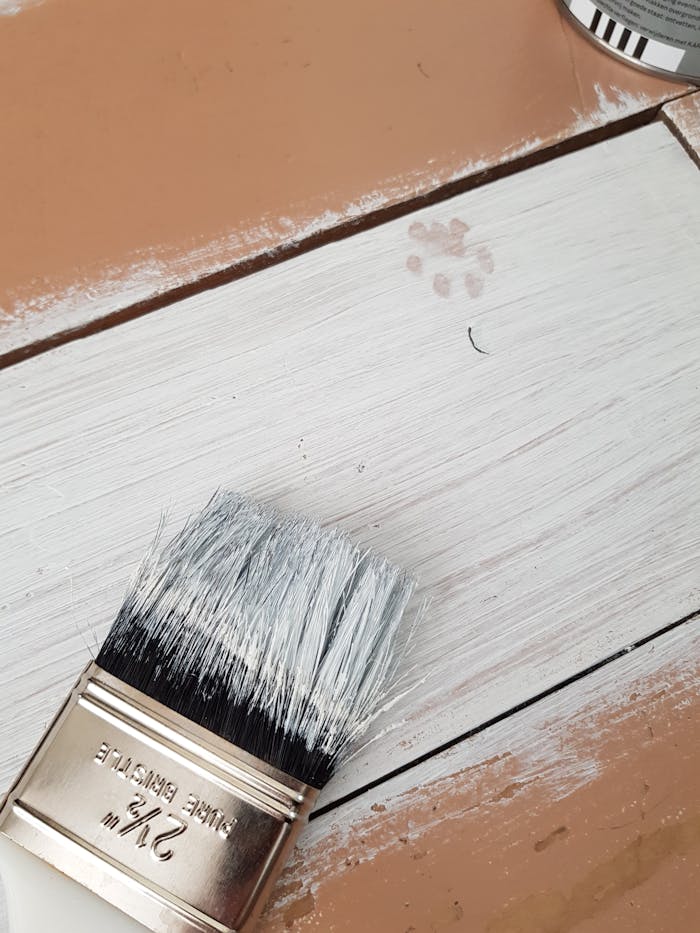 The Art of Drawing Readers In: Your attractive post title goes here Detailed view of a paintbrush on a wood surface with a paw print, capturing the painting process